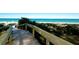 Convenient wooden boardwalk leading to pristine sandy beach with clear blue waters, providing easy access to paradise at 805 N Bay Blvd, Anna Maria, FL 34216