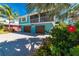 Inviting two-story teal beach home featuring a screened porch, two-car garage, and tropical landscaping at 805 N Bay Blvd, Anna Maria, FL 34216