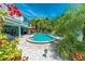 Backyard pool surrounded by tropical landscaping with outdoor seating and a nearby grill at 805 N Bay Blvd, Anna Maria, FL 34216