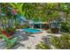 Nice pool with pavers surrounded by tropical plants in the backyard with colorful chairs in the background at 805 N Bay Blvd, Anna Maria, FL 34216
