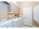 Well-equipped laundry room with a white washer, dryer, overhead cabinets, and ample counter space for folding at 108 Amora Ave, Venice, FL 34285