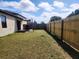 Grassy backyard with a stained wood fence, sunshade sail, grill, and a patio at 1107 22Nd E St, Palmetto, FL 34221