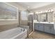 Bathroom featuring a soaking tub, glass-enclosed shower, and double sink vanity at 11499 Renaissance Blvd, Venice, FL 34293