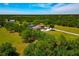 Expansive aerial view featuring a house, a pond, long driveway, and verdant landscape showcasing the property's grandeur at 1208 Oak Hammock Rd, Sarasota, FL 34240