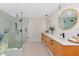 Bathroom with double sink wood vanity, round mirrors, and glass enclosed shower at 1208 Oak Hammock Rd, Sarasota, FL 34240