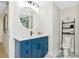 Stylish bathroom featuring a blue vanity, round mirror, and unique floral decor at 1208 Oak Hammock Rd, Sarasota, FL 34240