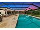 Screened pool with stone surround, lounge seating and mature trees offers a relaxing outdoor space at 1208 Oak Hammock Rd, Sarasota, FL 34240