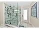 Beautifully tiled glass shower with rainfall shower head, hand held, and a pebble floor at 1208 Oak Hammock Rd, Sarasota, FL 34240