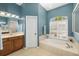 Bright bathroom featuring a soaking tub, tiled floors, wooden vanity, and plenty of natural light at 12810 Kite Dr, Bradenton, FL 34212
