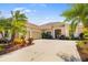 Beautiful home exterior featuring a three-car garage, mature palms, and lush landscaping at 12810 Kite Dr, Bradenton, FL 34212