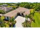 Aerial view of a charming home with a tile roof, lush landscaping, and a spacious driveway with a pond view at 12810 Kite Dr, Bradenton, FL 34212