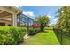 Landscaped backyard with vibrant plants, lush green grass, enclosed screen patio, and a black fence around the yard at 12822 Kite Dr, Bradenton, FL 34212