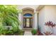 Elegant entryway with a double-door entrance, decorative glass, and lush tropical landscaping at 12822 Kite Dr, Bradenton, FL 34212