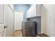Well-lit laundry room with white cabinets, utility sink, and modern washer and dryer at 12822 Kite Dr, Bradenton, FL 34212
