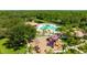 Aerial view of a playground and pool with mature trees, a splash pad, and tennis courts within the community at 12822 Kite Dr, Bradenton, FL 34212