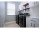 Organized laundry room with modern washer and dryer, storage cabinets, and open shelving at 12841 Balsam Ter, Bradenton, FL 34212
