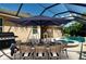 Outdoor dining under a shade umbrella in a screened-in patio with a pool, ideal for entertaining at 12841 Balsam Ter, Bradenton, FL 34212