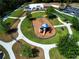 Aerial view of a playground featuring a colorful play structure, surrounded by lush green grass and walking paths at 12841 Balsam Ter, Bradenton, FL 34212