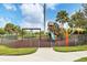 A fenced-in playground featuring a swing set, slide, and play structure on a safety-surfaced ground at 1294 Riverscape St # D, Bradenton, FL 34208