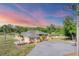 Expansive ranch home showcases lush tropical landscaping, circular drive, and a picturesque sunset backdrop at 1668 Tropicaire Blvd, North Port, FL 34286