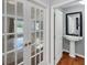 Hallway with French doors, hardwood flooring, and a partial view of a bathroom with a pedestal sink at 1668 Tropicaire Blvd, North Port, FL 34286