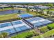 Aerial view of tennis, pickle ball, and basketball courts next to a lake in a planned community at 17675 Azul Dr, Lakewood Ranch, FL 34202