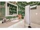 Eclectic bathroom with green zebra-print wallpaper, white vanity, and a shower/tub combo with a curtain at 21221 Wacissa Dr, Venice, FL 34293