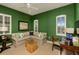 Comfortable living room with green walls, a neutral sectional sofa, bamboo coffee table, and natural light at 21221 Wacissa Dr, Venice, FL 34293