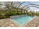 Private screened-in pool with lush landscaping, a cascading water feature, and brick pavers at 21221 Wacissa Dr, Venice, FL 34293