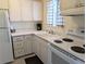 Classic kitchen features white appliances and cabinets, complemented by a black and white checkered window covering at 2340 Canal Dr # G-35, Bradenton, FL 34207