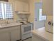Classic kitchen features white appliances and cabinets, complemented by a black and white checkered window covering at 2340 Canal Dr # G-35, Bradenton, FL 34207