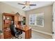 Well-lit home office featuring a built-in wooden bookshelf desk, ceiling fan, and window at 2628 Sapphire Blue Ln, Bradenton, FL 34211