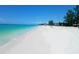 Beautiful view of a wide, sandy beach meeting clear turquoise water under a bright blue sky at 2703 Avenue B, Holmes Beach, FL 34217