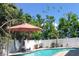 Backyard pool area with outdoor umbrella, privacy fence, and tropical landscaping in a sunny setting at 2703 Avenue B, Holmes Beach, FL 34217