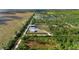 Aerial view of a property featuring a home and a large outbuilding, complemented by surrounding wooded areas and flatlands at 29527 Maris Dr, Punta Gorda, FL 33982