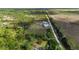 High-angle shot showcasing a home and a substantial outbuilding beside a dirt road and expansive open fields at 29527 Maris Dr, Punta Gorda, FL 33982