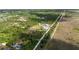 Aerial view capturing a home with a large outbuilding along a long driveway, bordered by trees and adjacent open fields at 29527 Maris Dr, Punta Gorda, FL 33982