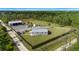 Aerial view of a fenced property featuring a home, a large outbuilding, and ample parking space on a grassy lot at 29527 Maris Dr, Punta Gorda, FL 33982
