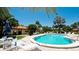 Community pool with lounge chairs, tables, lush palm trees, and a bright blue sky at 3112 Cambridge Ave # 6, Bradenton, FL 34207
