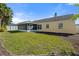 A large backyard with a manicured lawn, screened-in patio, and yellow house exterior at 3413 5Th W Dr, Palmetto, FL 34221