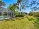 Expansive backyard with a screened-in pool area, mature trees, and lush landscaping for privacy at 3786 Surrey Ln, Sarasota, FL 34235