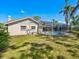 Back exterior view of a home showcasing the screened-in pool area, well-maintained lawn, and sunny skies at 3786 Surrey Ln, Sarasota, FL 34235