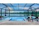 Serene screened-in pool area with comfortable lounge chairs offering picturesque views of a calm, reflective lake at 3811 158Th Avenue E Cir, Parrish, FL 34219