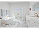 Bright bathroom featuring a soaking tub, double doors, and vanity with gold hardware at 4104 Las Palmas Way, Sarasota, FL 34238