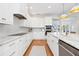 Modern white kitchen featuring marble countertops, stainless appliances, and herringbone backsplash at 4104 Las Palmas Way, Sarasota, FL 34238