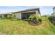 Manicured backyard featuring green grass, decorative landscaping, a dark metal fence, and a screened-in patio at 5406 Coral Reef Way, Lakewood Ranch, FL 34211