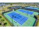 The aerial view shows several pristine tennis courts, with blue surfaces and green surroundings at 5406 Coral Reef Way, Lakewood Ranch, FL 34211