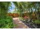 Lush backyard garden with a stone pathway, tropical plants, and privacy fencing for a tranquil outdoor experience at 5523 Scotia Pl, Sarasota, FL 34231