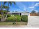 Inviting single-story home featuring a well-kept lawn, tropical palm trees, and a spacious driveway leading to the garage at 5523 Scotia Pl, Sarasota, FL 34231