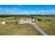 Aerial view of the home, driveway, barn, and surrounding green pastures on a clear day at 5949 225Th E St, Bradenton, FL 34211